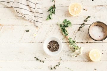 Cosmetici naturali fatti in casa con ingredienti biologici, oli essenziali e piante su un tavolo di legno.